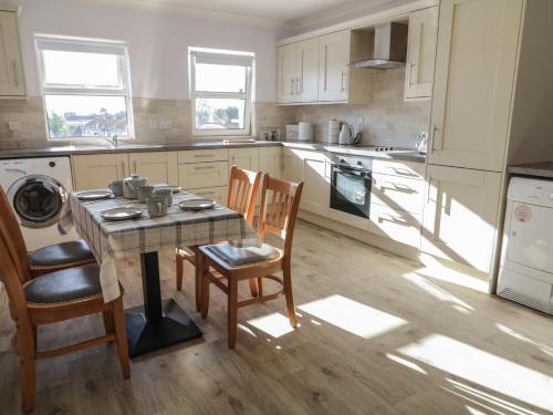 a kitchen with a table and two chairs and a table and a stove at Shalom Apartment 100A in Armagh