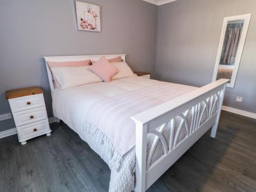 a bedroom with a white bed with pink pillows at Shalom Apartment 100A in Armagh
