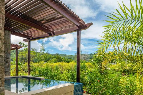 an outdoor swimming pool with a wooden pergola at Canopy By Hilton Seychelles Resort in Anse a La Mouche
