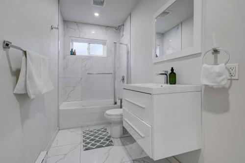 a white bathroom with a toilet and a shower at The NDG Escape Prime Location and Cozy Stay in Montréal