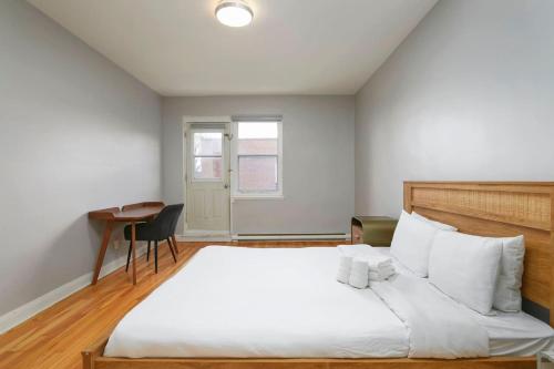 Un dormitorio con una gran cama blanca y un escritorio. en Lovely 2BR on Walkley, en Montreal