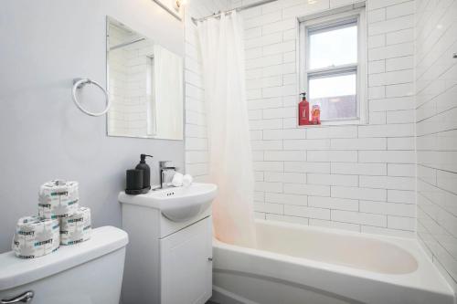 Baño blanco con bañera blanca y lavamanos en Lovely 2BR on Walkley, en Montreal