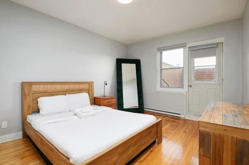 Un dormitorio con una gran cama blanca y una ventana. en Amazing 2BR on Walkley, en Montreal