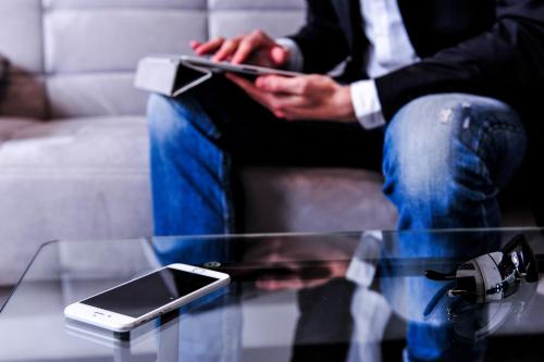 a man sitting on a couch with a cell phone on a table at Brick House Treviso in Treviso