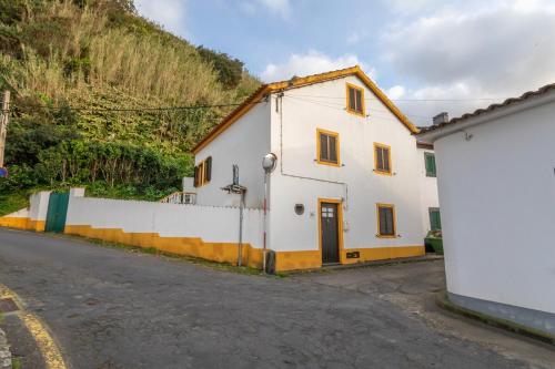 a white house on the side of a road at GuestReady - Casa dos Moinhos near the beach in Porto Formoso