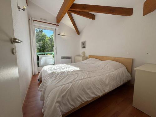 une chambre avec un lit et une grande fenêtre dans l'établissement Maison mitoyenne en duplex avec jardin proche lac, à Biscarrosse
