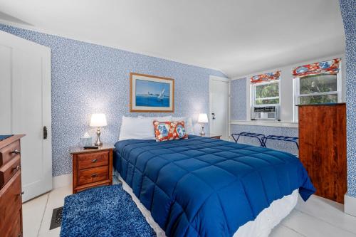 a blue bedroom with a bed and a dresser and windows at 89 Gorham Road Harwich Port - Sweet Retreat in Harwich Port