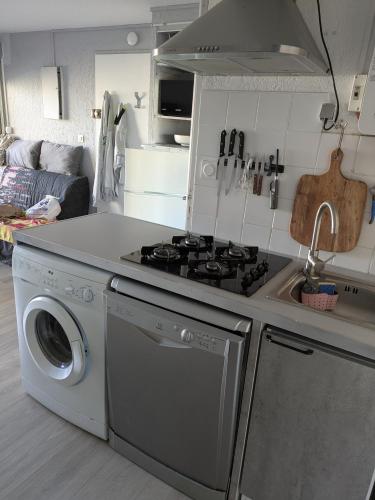 une cuisine avec une cuisinière et une machine à laver dans l'établissement appartement Cap d'Agde, au Cap d'Agde