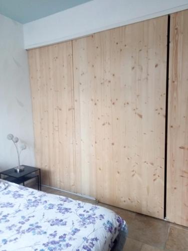 a bedroom with a wooden wall with a bed at Appartement au rez-de-chaussée in Souillac