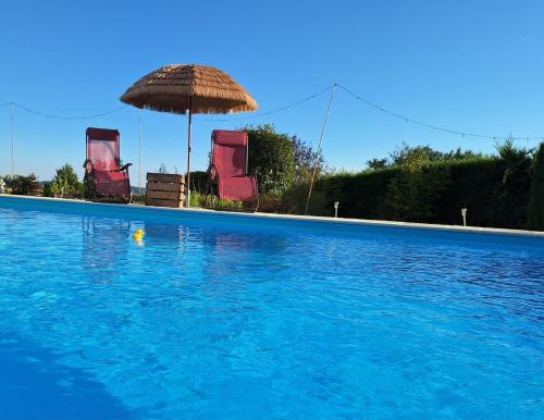 a swimming pool with two chairs and an umbrella at Favau in Villeneuve-sur-Lot