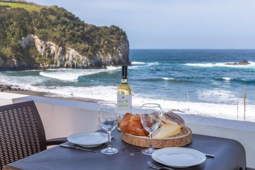 a table with a bottle of wine and a basket of bread and wine glasses at GuestReady - Beachfront Casa da Praia in Porto Formoso