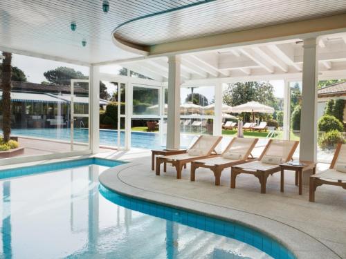 a swimming pool with white chairs and a swimming at Villa Favorita - Parkhotel Delta in Ascona
