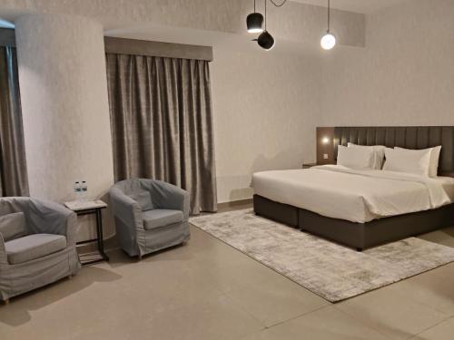 a bedroom with a large bed and two chairs at VOGO Grand Hotel Formerly Best Western Plus Hotel Dubai Academic City in Dubai