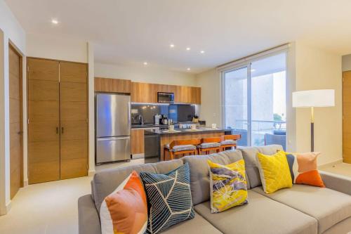 a living room with a gray couch with colorful pillows at Oceanview Stay Pools Walk to Beach & Snorkel in Akumal
