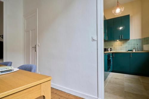 une cuisine avec des placards verts et une table en bois dans l'établissement Appart lumineux, 4P, balcon, proche marché, à Lille