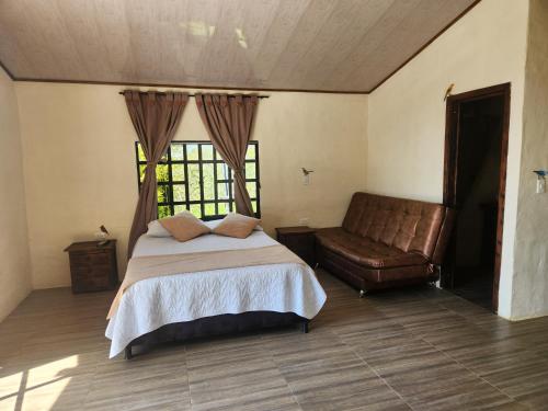 a bedroom with a bed and a leather couch at Finca QUINTA SAN JUAN in El Reposo