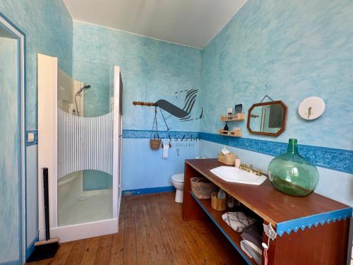 La salle de bains bleue est pourvue d'un lavabo et d'une douche. dans l'établissement Maison M - Spacieuse maison avec piscine privative, à Tonnay-Charente