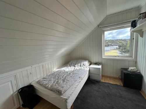 a small bedroom with a bed and a window at Sommerferie i skjærgårdsidyll på Langenes i Kristiansand in Kristiansand