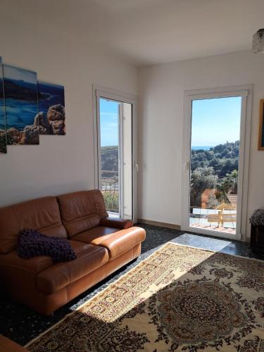 a living room with a couch and two large windows at VistaBlu Bussana in Arma di Taggia