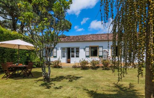 a white house with a table and an umbrella at GuestReady - Domus Adepta Charming w/ Garden in Furnas