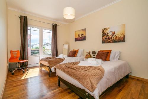 a bedroom with two beds and a chair at GuestReady - Casa do Parque in Ponta Delgada