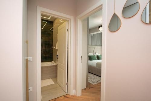 a hallway leading to a bathroom with a bed and a tub at Luxe Apartment - NEO TOWER in Suceava