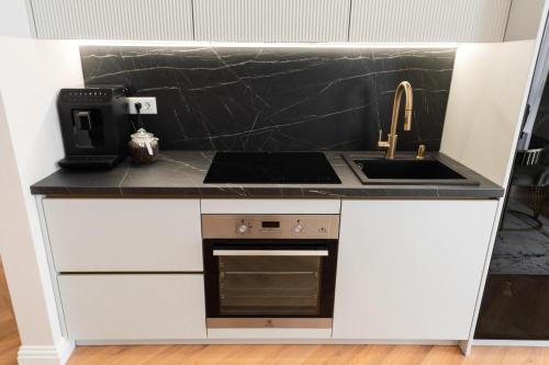 a kitchen with a counter with a sink and a stove at Luxe Apartment - NEO TOWER in Suceava