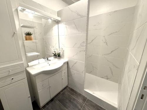 une salle de bain blanche avec un lavabo et un miroir dans l'établissement CC G Le Jardin du Mont Rabeau, à Nice