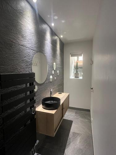 une salle de bain noire avec un lavabo et un miroir dans l'établissement La terrasse des épices, à Caluire-et-Cuire