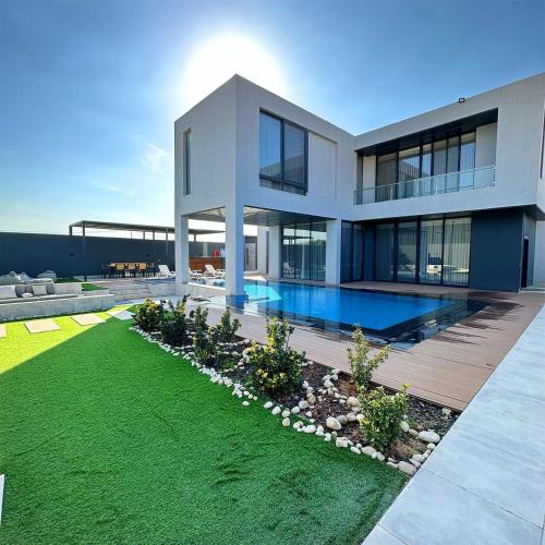 a large house with a swimming pool in front of it at Bow Villa in Sowayma