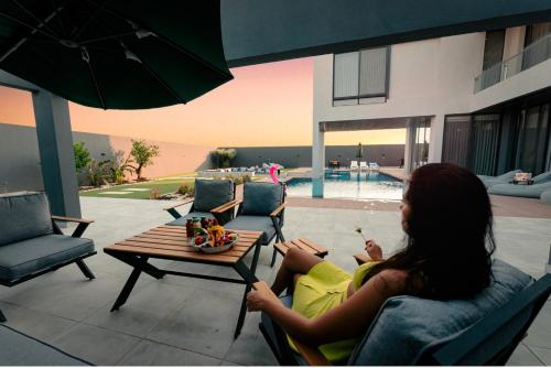 a woman sitting in a chair next to a table at Bow Villa in Sowayma