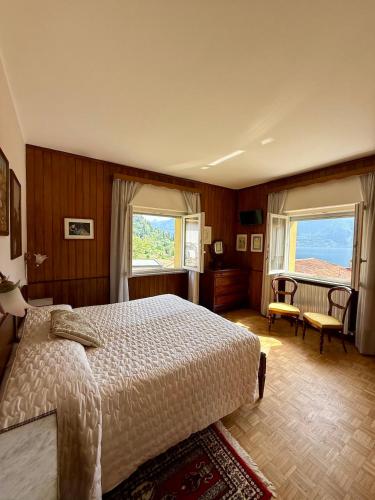 a bedroom with a large bed and two windows at Ersilia ed Ennio Apartment in Bellagio