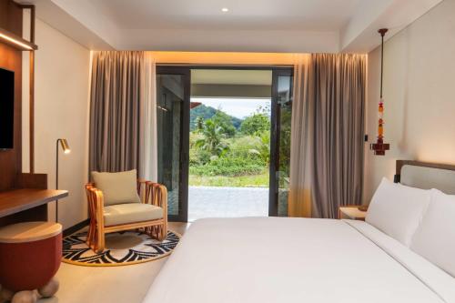 a bedroom with a bed and a chair and a window at Canopy By Hilton Seychelles Resort in Anse a La Mouche