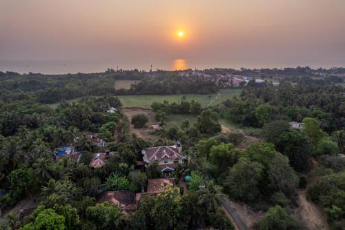 an aerial view of a house with the sunset in the background at Palm Grove Cottages - Leisure Resort in Benaulim