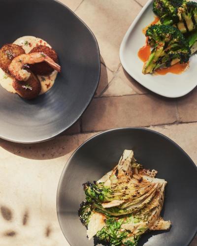 a table with three plates of food with broccoli and shrimp at IZZA Marrakech in Marrakech
