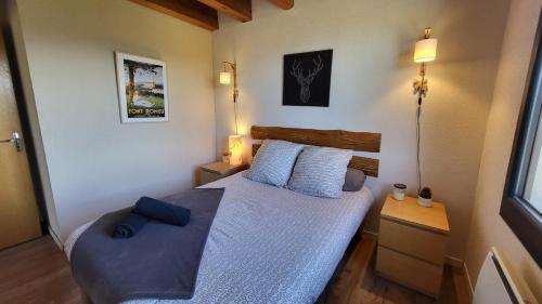 Schlafzimmer mit einem Bett mit blauer Bettwäsche und Kissen in der Unterkunft Maison cosy, garage, jardin, terrasse vue montagne in Font Romeu Odeillo Via