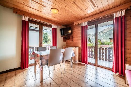 a dining room with a table and chairs and windows at La Flèche d'Or in Châtel