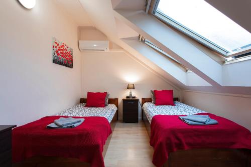two beds in a attic room with red pillows at Lucsony Apartman in Mosonmagyaróvár