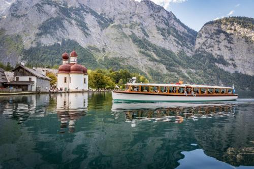 a boat on the water with mountains in the background at Haus BergGesundZeit Doppelzimmer Kärlingerhaus in Schönau am Königssee