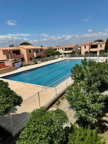 une grande piscine avec une passerelle à côté de certains bâtiments dans l'établissement Studio 723 - village naturiste Aphrodite, à Leucate-Plage