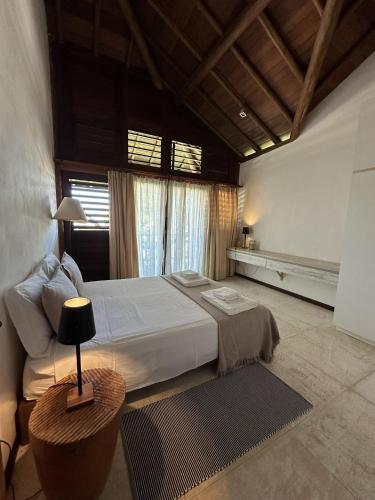 une chambre avec un grand lit blanc et une table dans l'établissement App Elisabeth Kite Village, à Uruau