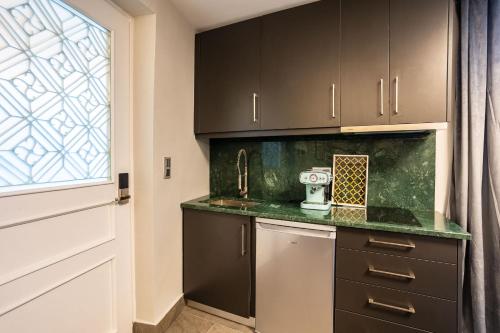 a kitchen with black cabinets and a window at The Secret Garden - Courtyard & Private Pool Villa in Kalamata