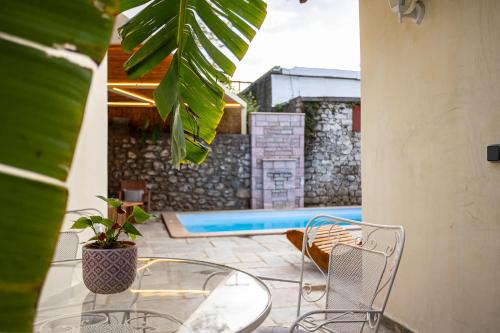 a patio with a glass table and chairs and a pool at The Secret Garden - Courtyard & Private Pool Villa in Kalamata