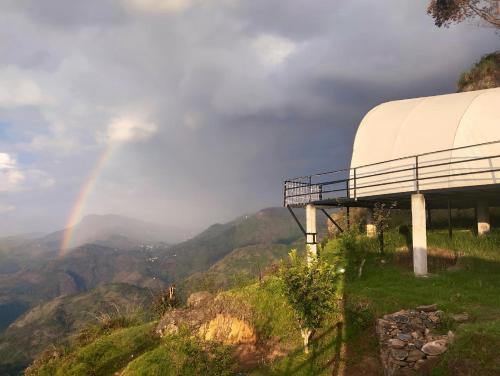 a rainbow in the sky over a mountain at Cocoon Creek in Kodaikānāl