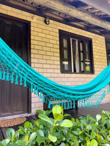 a blue hammock in front of a house at Haleakala Hostel & Pousada in Praia do Rosa