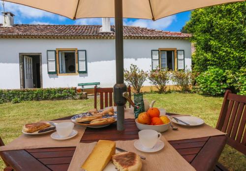 a wooden table with food on it with an umbrella at Domus Adepta Family w Garden in Furnas