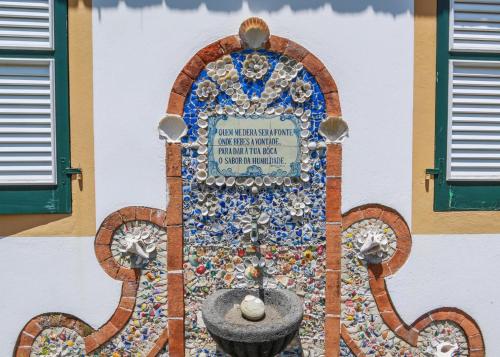 a mosaic tile wall with a fountain on a building at Domus Adepta Family w Garden in Furnas