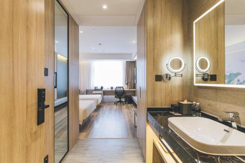 a bathroom with a sink and a bedroom at Atour Hotel Shanghai Anting in Shanghai