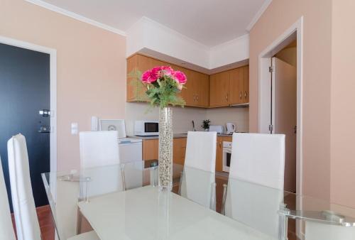 a dining room with a table and a vase with a flower at Alvor Sol in Alvor
