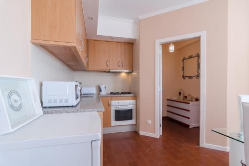 a kitchen with white appliances and wooden cabinets at Alvor Sol in Alvor